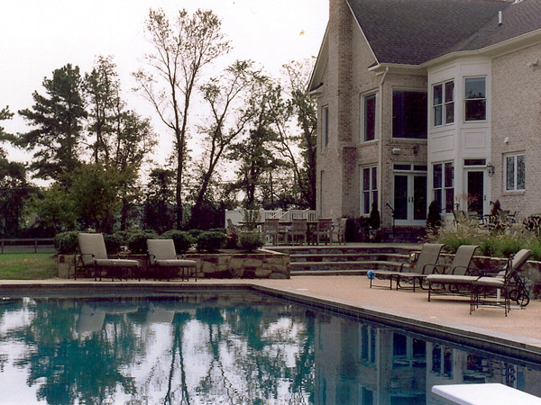 Modern inredning av en mellanstor anpassad pool på baksidan av huset, med naturstensplattor