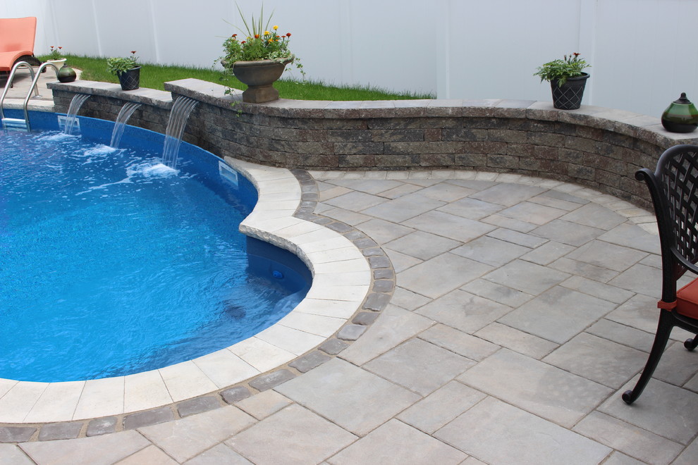 Diseño de piscina con fuente pequeña a medida en patio trasero con adoquines de hormigón