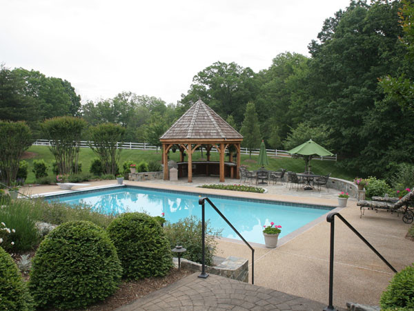 Ejemplo de piscina actual grande rectangular en patio trasero con adoquines de piedra natural