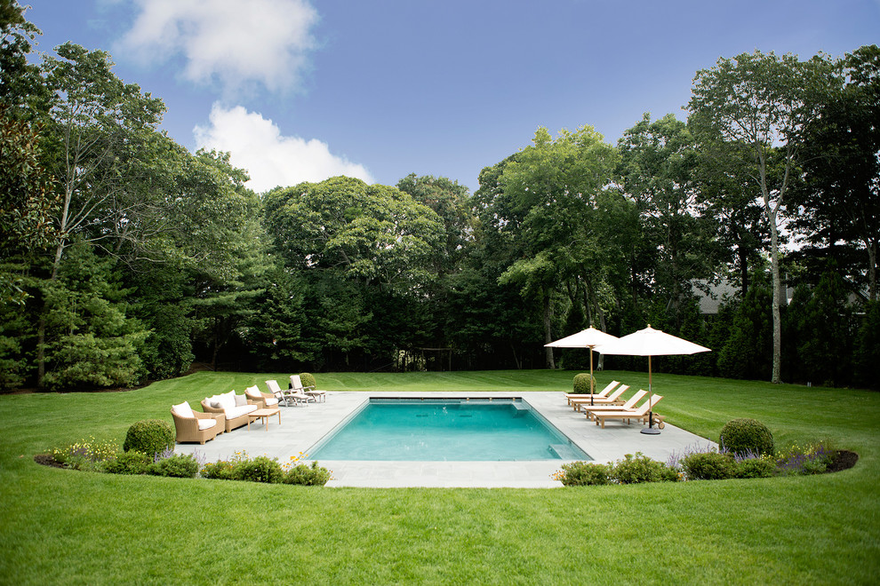 Ejemplo de piscina clásica grande rectangular en patio trasero con adoquines de piedra natural