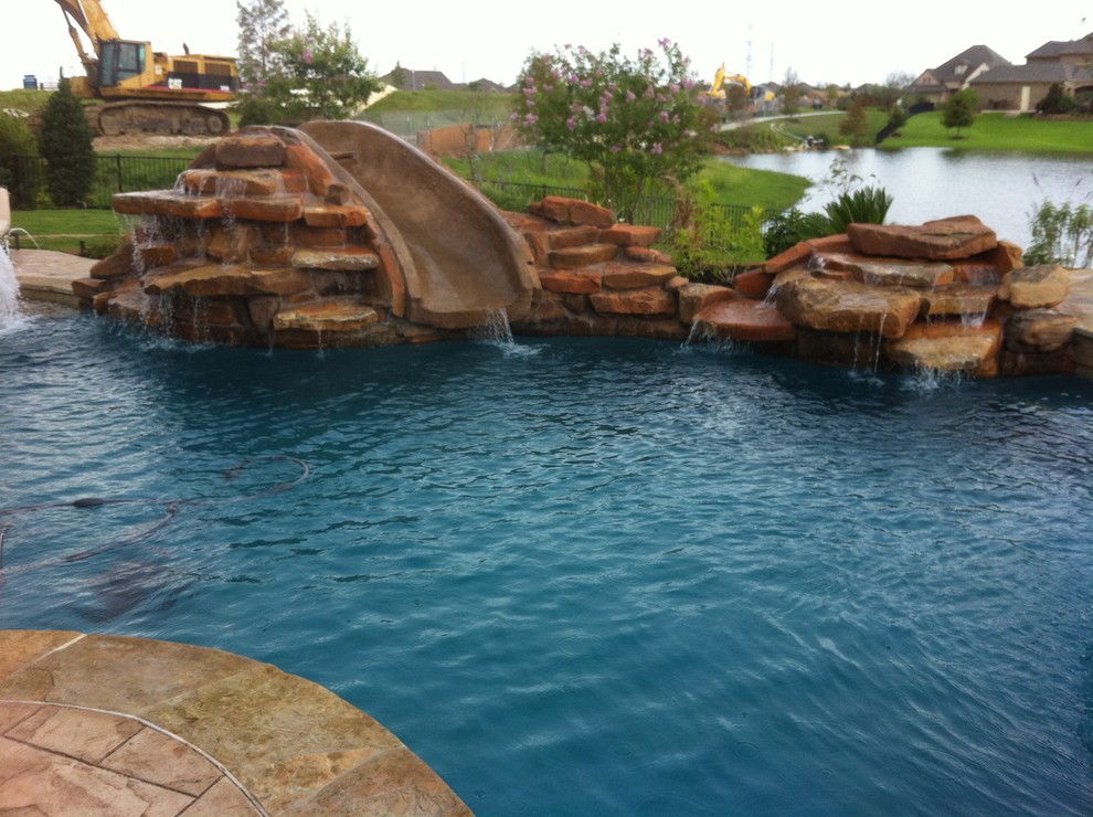 ヒューストンにある中くらいなトラディショナルスタイルのおしゃれなプール (ウォータースライダー、天然石敷き) の写真