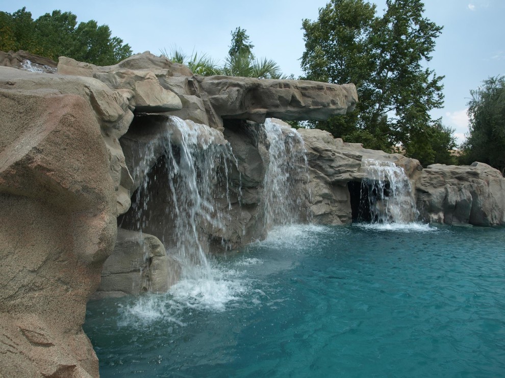 Foto di un'ampia piscina naturale tropicale personalizzata dietro casa con un acquascivolo e pavimentazioni in pietra naturale