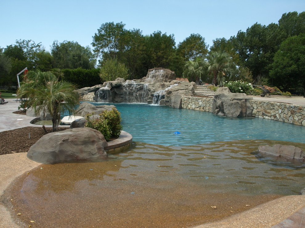 Пример оригинального дизайна: огромный естественный бассейн произвольной формы на заднем дворе в морском стиле с водной горкой и покрытием из каменной брусчатки