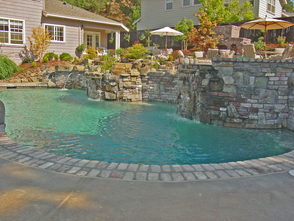 Idee per una grande piscina monocorsia rustica a "C" dietro casa con fontane e cemento stampato