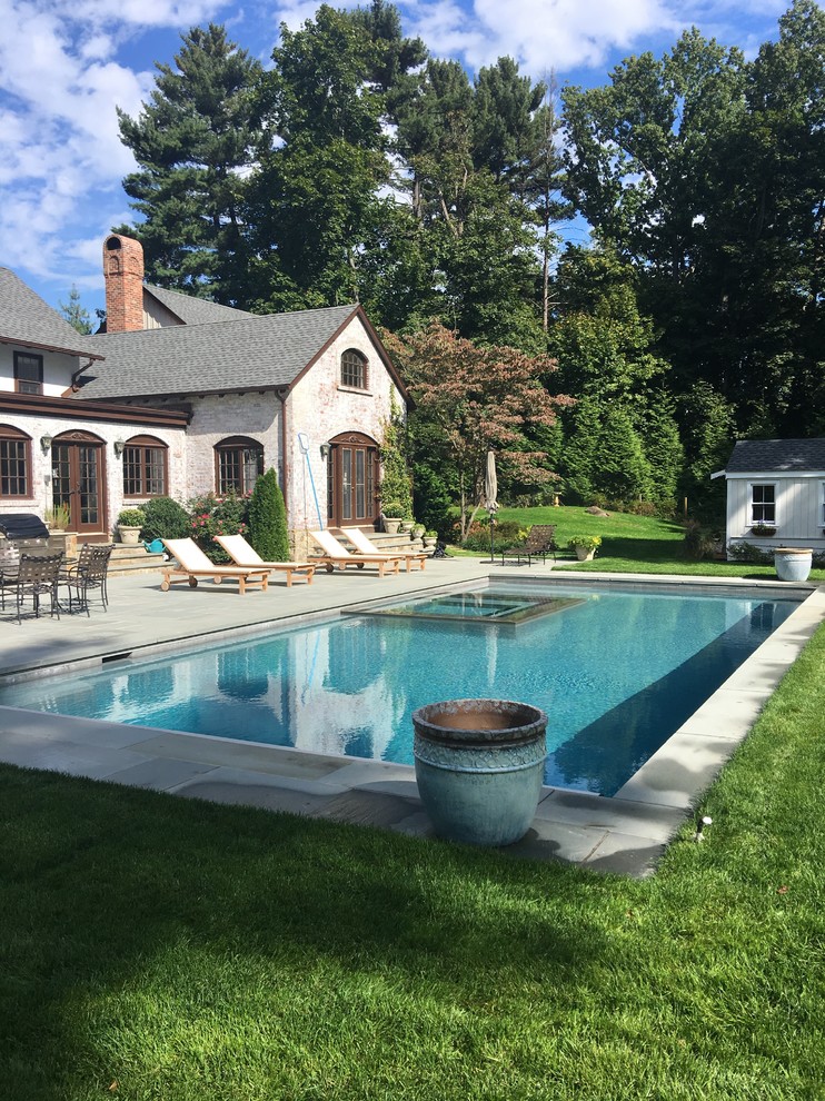 Exempel på en stor klassisk rektangulär pool på baksidan av huset, med spabad och naturstensplattor