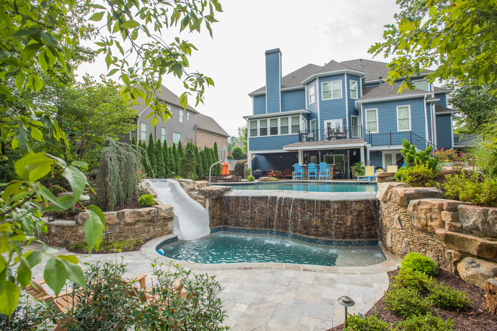 Idee per un'ampia piscina naturale tropicale personalizzata dietro casa con un acquascivolo