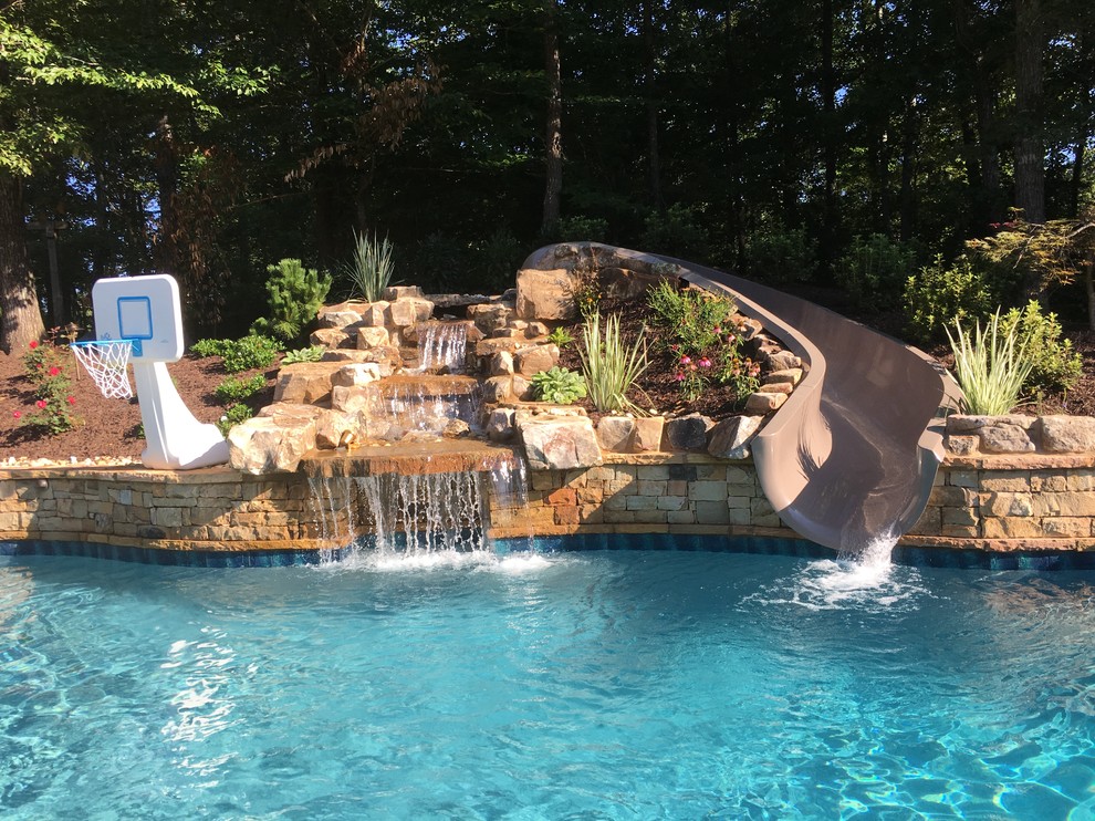 Photo of an expansive world-inspired back custom shaped natural swimming pool in Atlanta with a water slide.