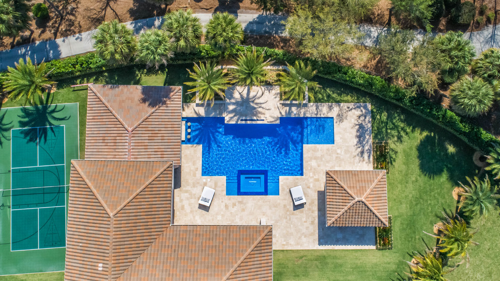 Cette image montre une grande piscine arrière minimaliste rectangle avec un bain bouillonnant et des pavés en pierre naturelle.