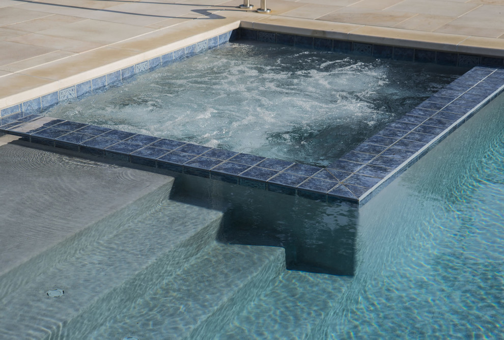 Ejemplo de piscinas y jacuzzis de tamaño medio rectangulares en patio trasero con adoquines de piedra natural