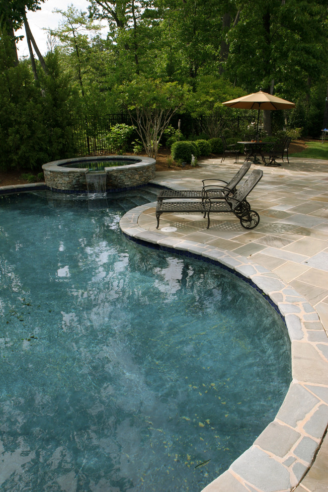 Идея дизайна: большой бассейн произвольной формы на заднем дворе в современном стиле с покрытием из каменной брусчатки и джакузи