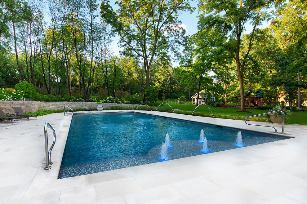 Diseño de piscina con fuente alargada tradicional grande rectangular en patio trasero con suelo de baldosas