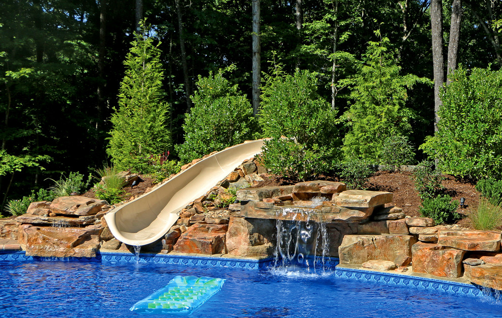 Modelo de piscina con tobogán rústica en patio trasero con adoquines de piedra natural