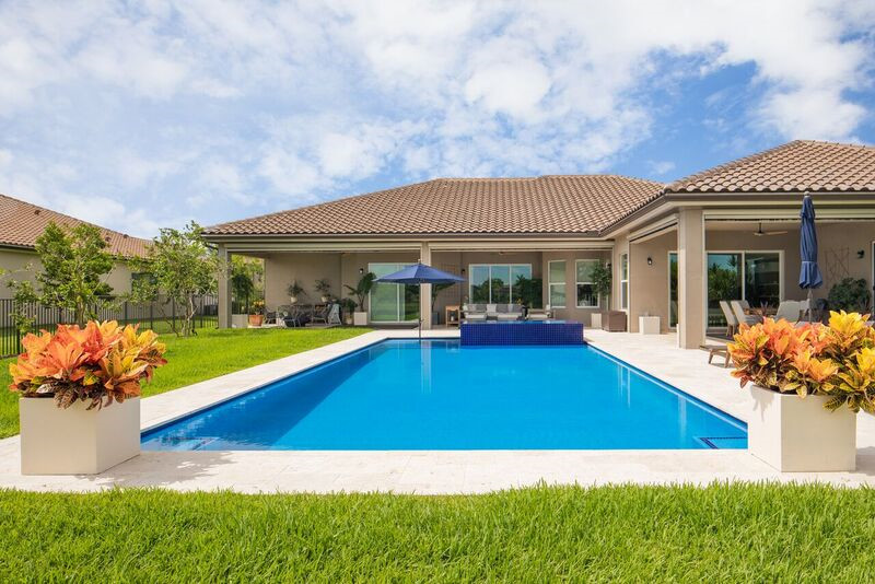 Diseño de piscina alargada minimalista grande rectangular en patio trasero con adoquines de piedra natural