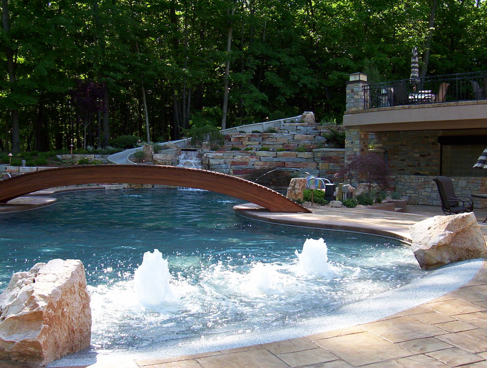 Example of a large transitional backyard stamped concrete and custom-shaped water slide design in Grand Rapids