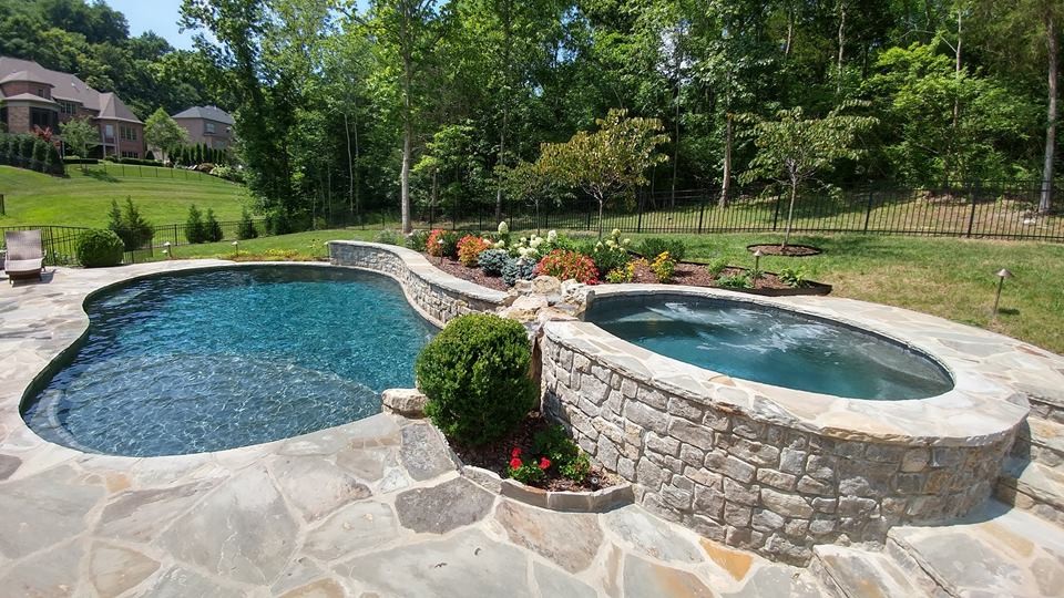 Foto di una piscina monocorsia american style a "C" di medie dimensioni e dietro casa con una vasca idromassaggio e pavimentazioni in pietra naturale