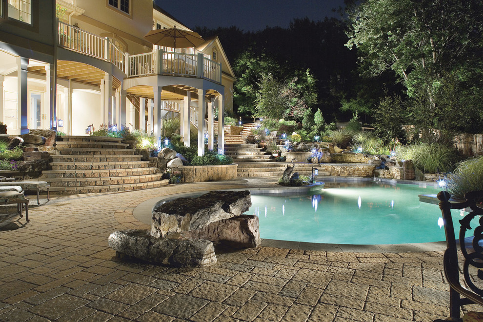 Ejemplo de piscina con fuente mediterránea grande tipo riñón en patio trasero con adoquines de piedra natural