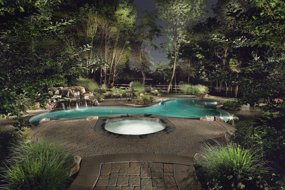 Modelo de piscina con fuente natural tradicional grande a medida en patio trasero con adoquines de piedra natural