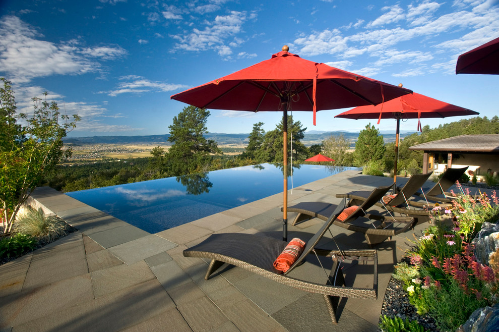 Ejemplo de piscina con fuente infinita moderna grande rectangular en patio trasero con adoquines de piedra natural