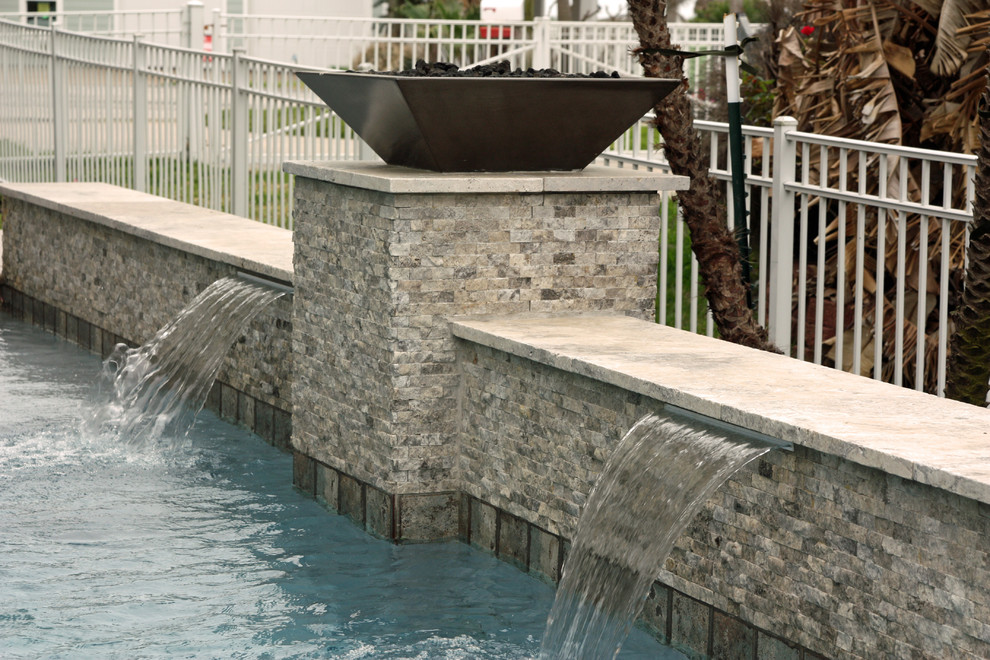 Exemple d'une petite piscine naturelle et latérale chic sur mesure avec un bain bouillonnant et des pavés en pierre naturelle.