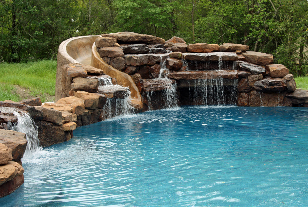 Esempio di una grande piscina naturale tradizionale personalizzata dietro casa con un acquascivolo e pavimentazioni in pietra naturale