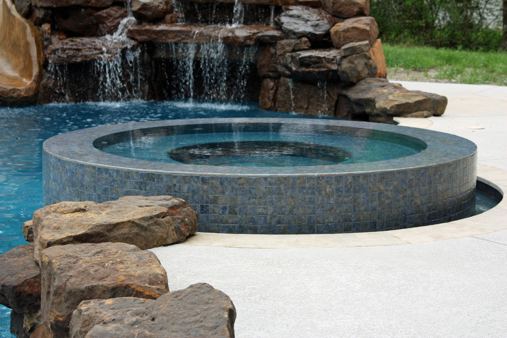 Diseño de piscina con tobogán natural clásica grande a medida en patio trasero con adoquines de piedra natural