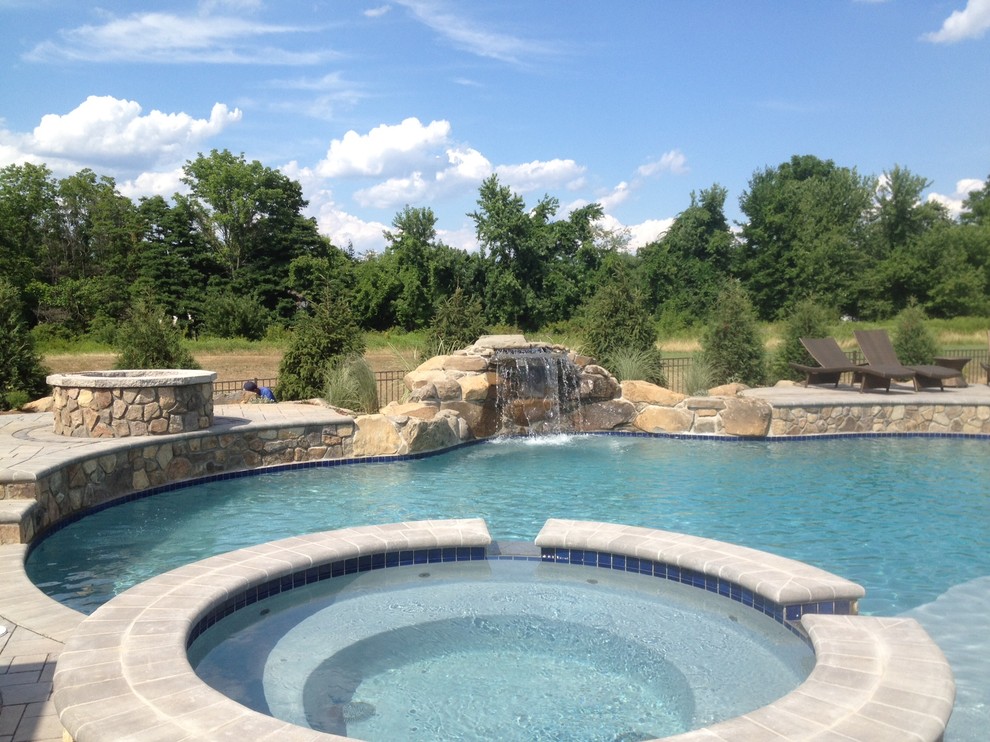 Ispirazione per una grande piscina naturale minimal personalizzata dietro casa con una vasca idromassaggio e pavimentazioni in cemento