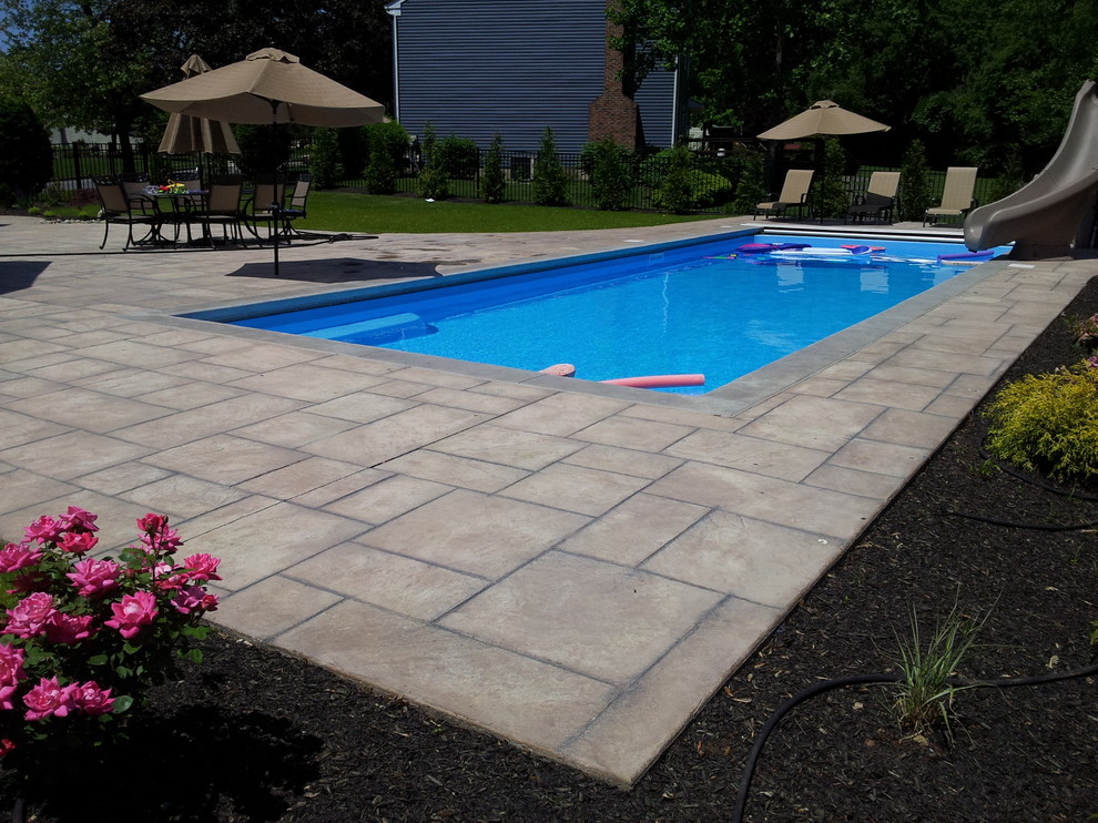 Medium sized classic back rectangular lengths swimming pool in Philadelphia with a water slide and concrete paving.