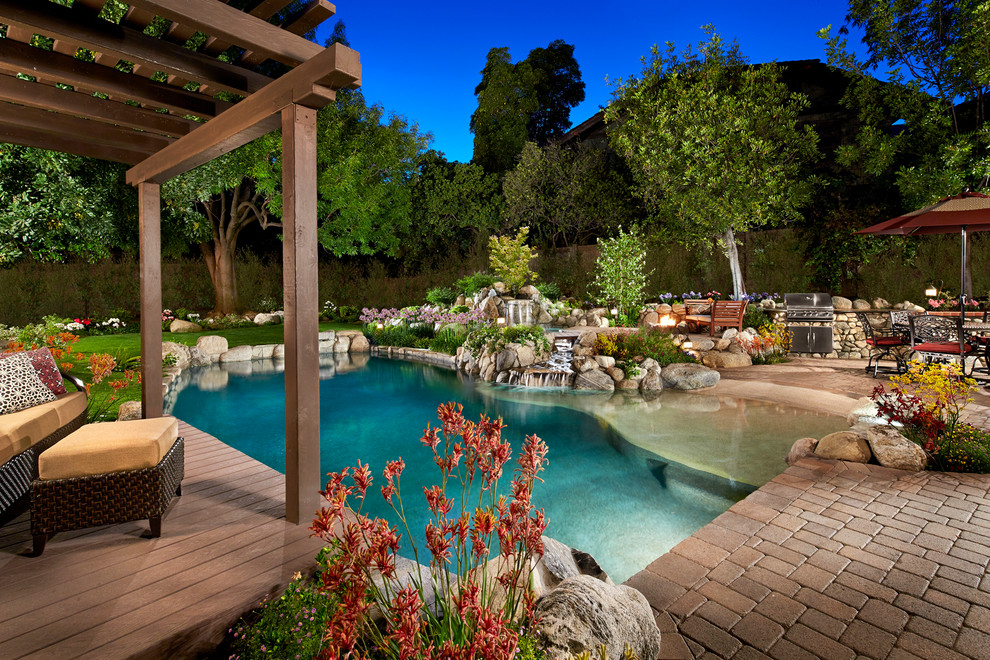 Diseño de piscina con fuente natural clásica renovada grande a medida en patio trasero con adoquines de ladrillo