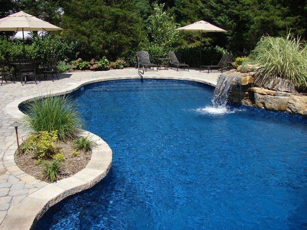 Idée de décoration pour une piscine naturelle et arrière tradition sur mesure avec un point d'eau et des pavés en pierre naturelle.