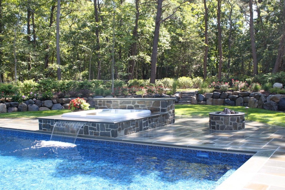 Immagine di una grande piscina naturale chic rettangolare dietro casa con fontane e pavimentazioni in pietra naturale