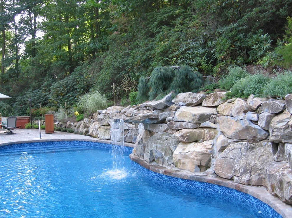 На фото: большой естественный бассейн произвольной формы на заднем дворе в классическом стиле с фонтаном и мощением тротуарной плиткой