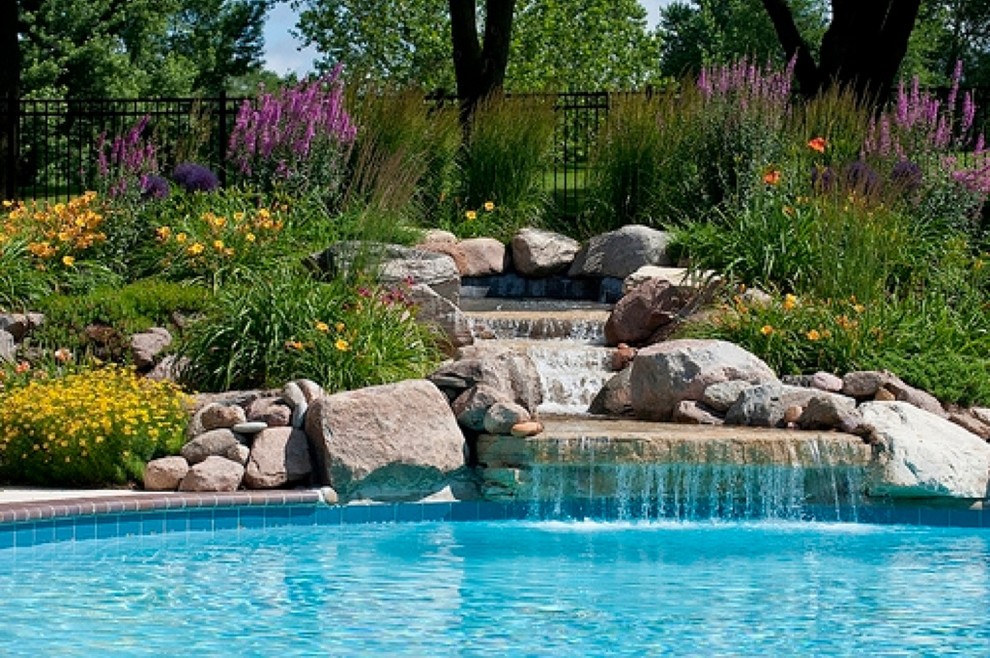 Esempio di una piscina naturale classica personalizzata dietro casa con una vasca idromassaggio e pavimentazioni in pietra naturale