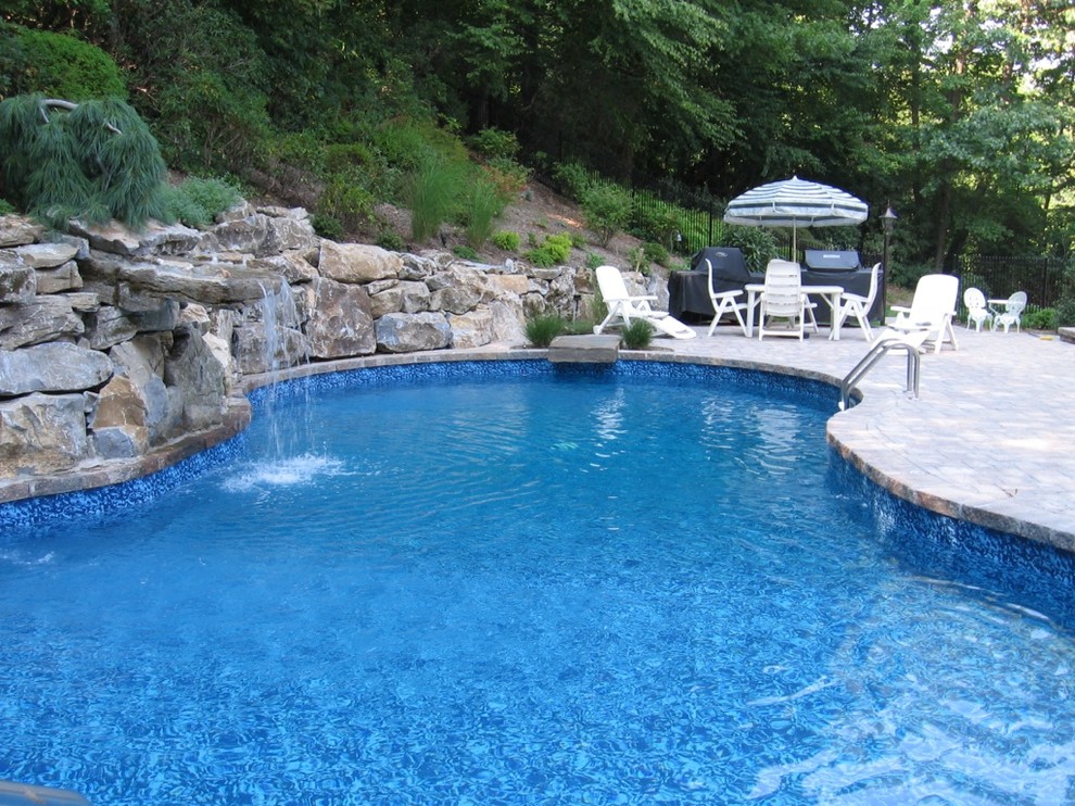 Foto de piscina con fuente natural tradicional grande a medida en patio trasero con adoquines de hormigón
