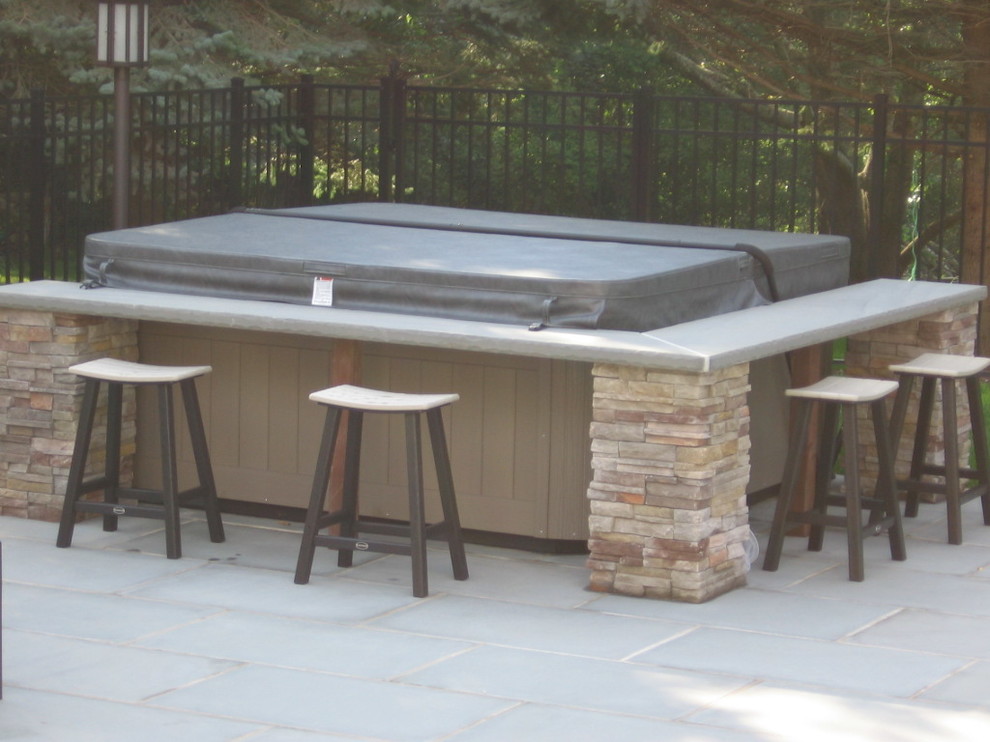Example of a classic backyard stone and custom-shaped natural hot tub design in New York