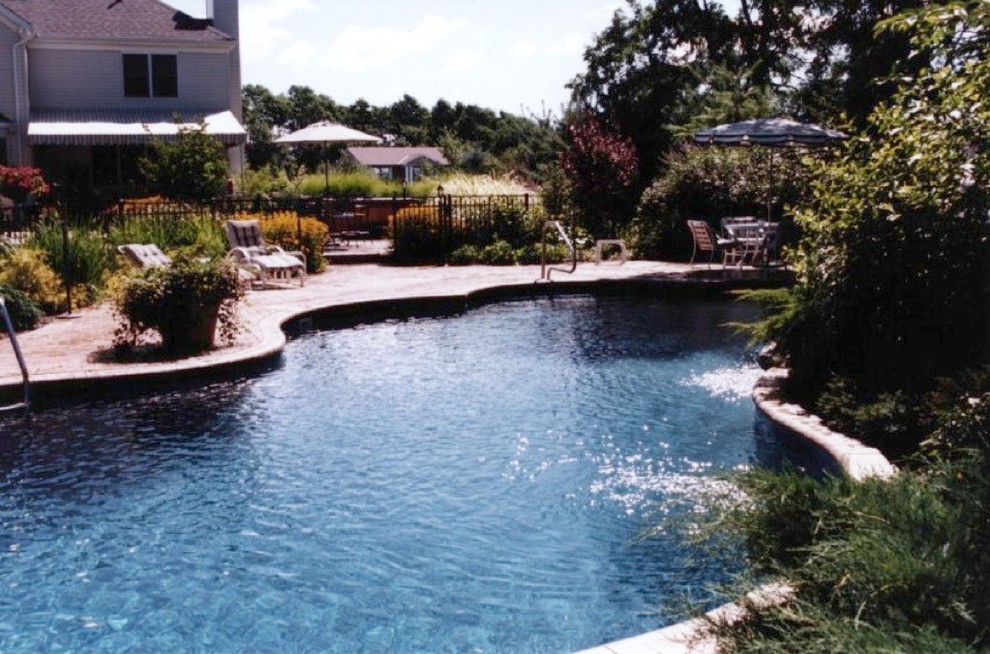 Design ideas for a large classic custom shaped natural swimming pool in New York with brick paving.