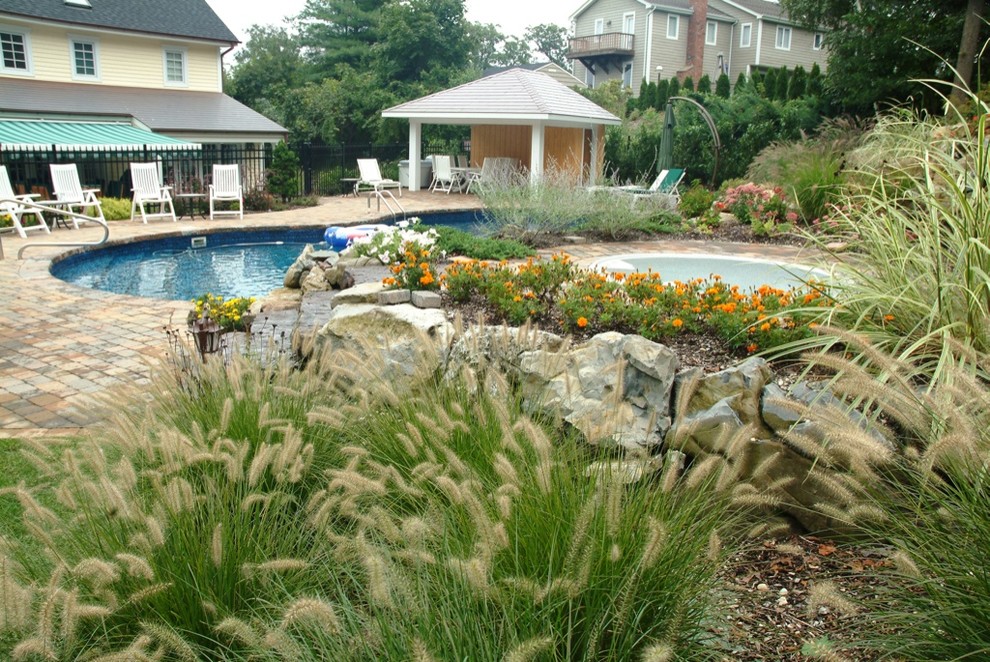 Diseño de piscinas y jacuzzis naturales clásicos de tamaño medio redondeados en patio trasero con adoquines de hormigón