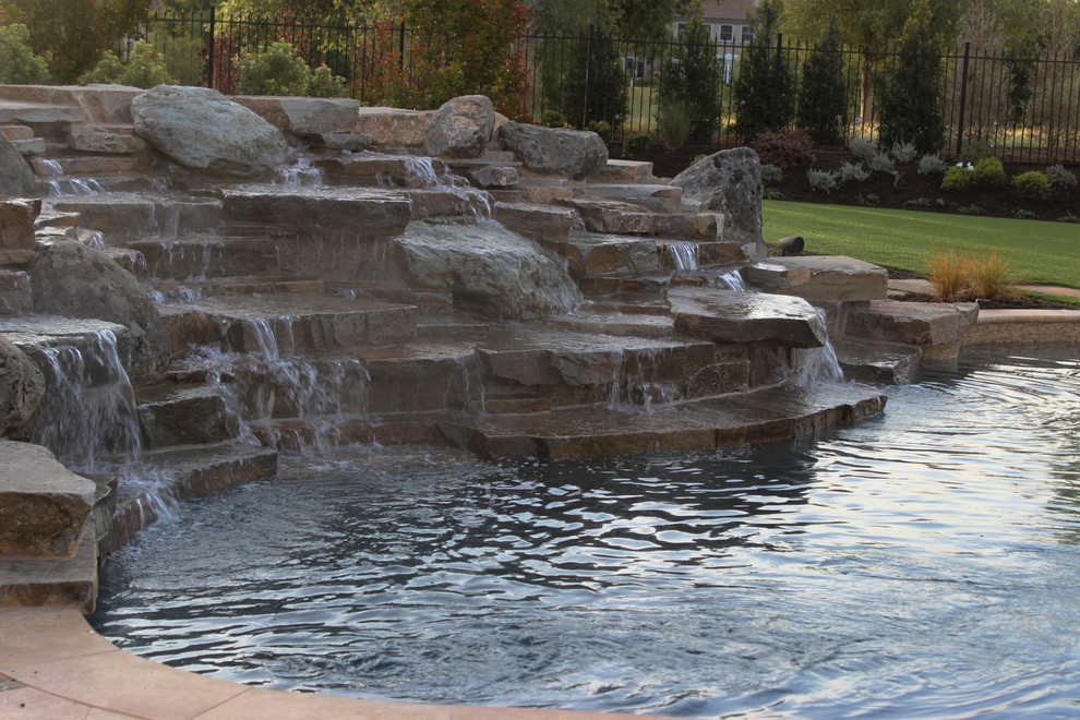 Esempio di una grande piscina naturale chic personalizzata dietro casa con fontane e pavimentazioni in pietra naturale