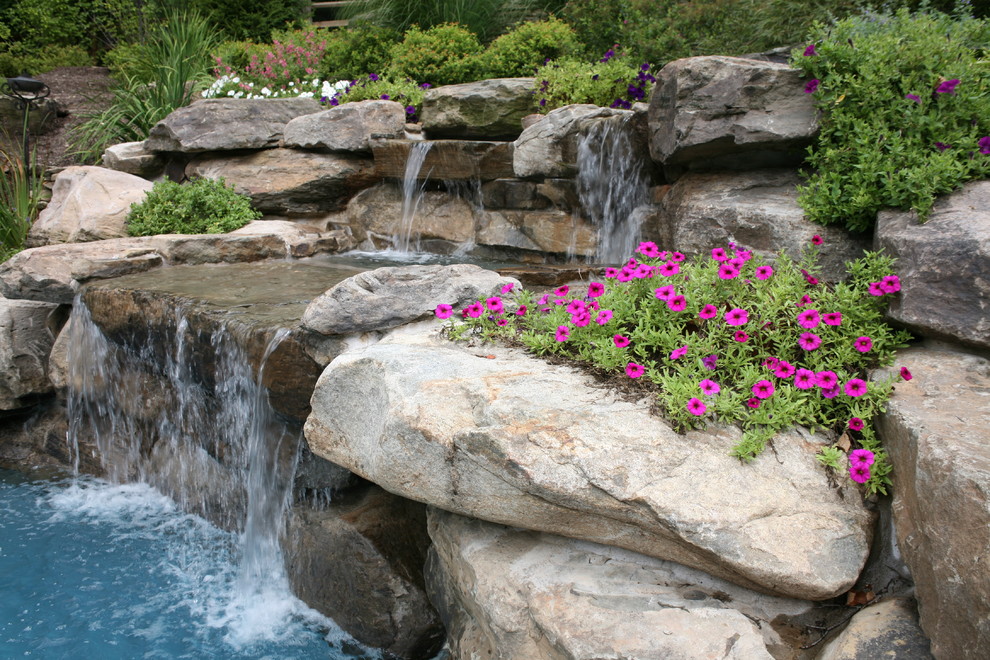 Inspiration for a large classic back kidney-shaped natural swimming pool in New York with a water feature and natural stone paving.
