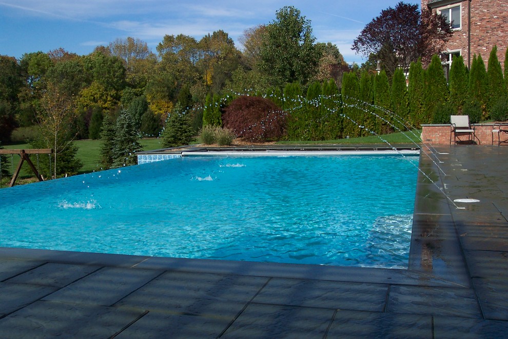 Ispirazione per una grande piscina monocorsia tradizionale rotonda dietro casa con pavimentazioni in cemento