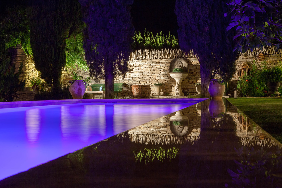 Пример оригинального дизайна: большой естественный, прямоугольный бассейн на заднем дворе в средиземноморском стиле с покрытием из каменной брусчатки