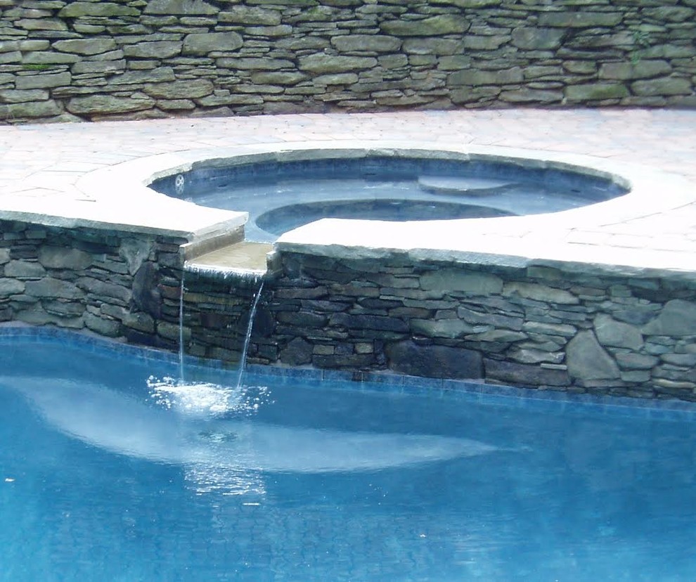 Immagine di una grande piscina tradizionale dietro casa con pavimentazioni in pietra naturale
