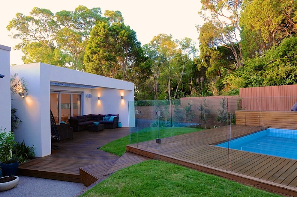 Foto de piscina alargada de tamaño medio en forma de L en patio trasero con entablado