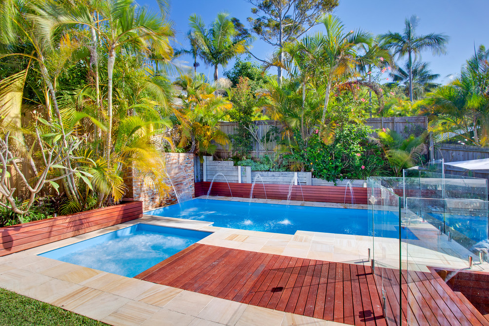 Esempio di una piscina costiera rettangolare di medie dimensioni e dietro casa con fontane e pedane
