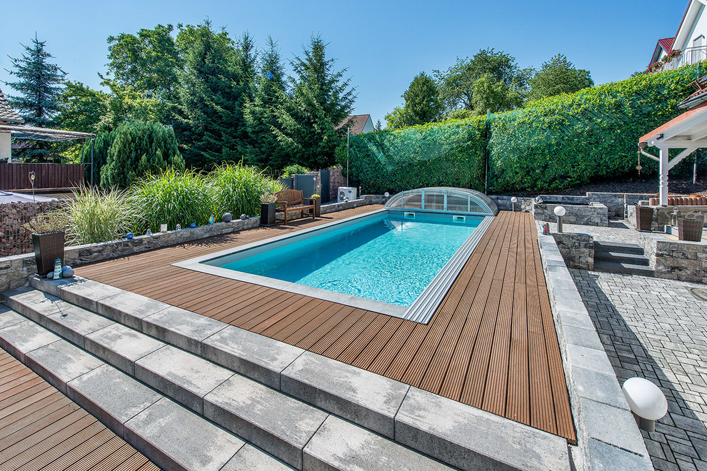 Modelo de piscina alargada contemporánea de tamaño medio rectangular en patio trasero con entablado
