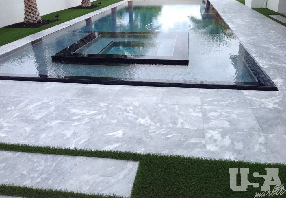 Hot tub - mid-sized modern backyard stone and rectangular infinity hot tub idea in Miami