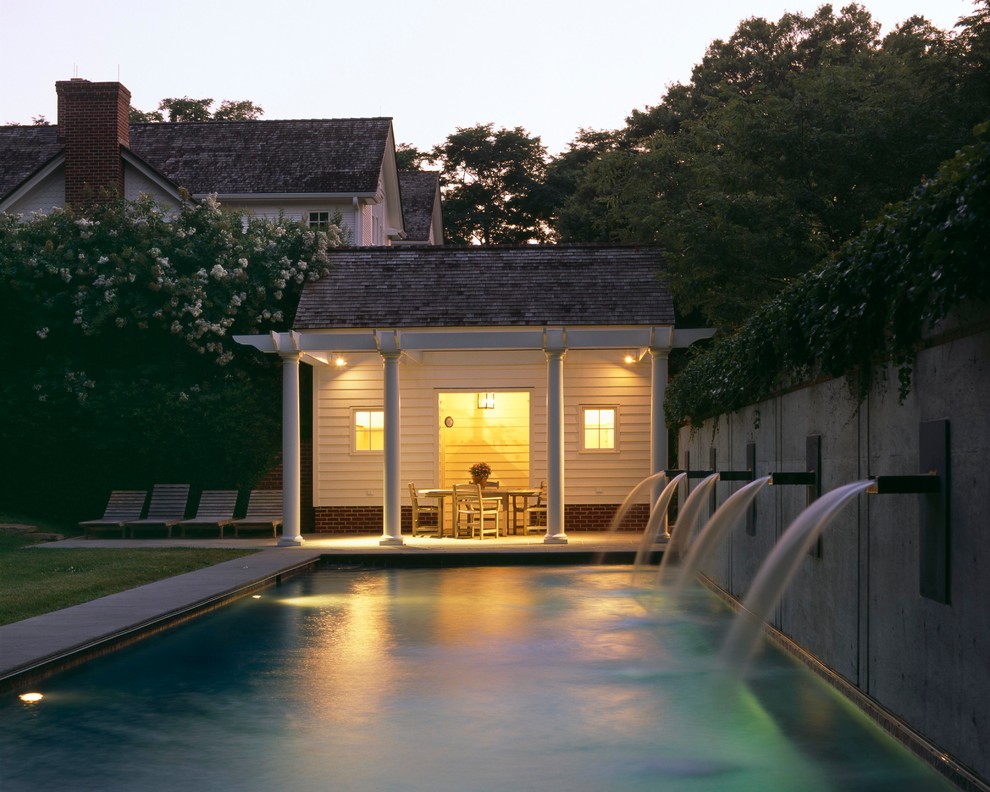 Ejemplo de piscina con fuente alargada tradicional de tamaño medio rectangular con adoquines de piedra natural