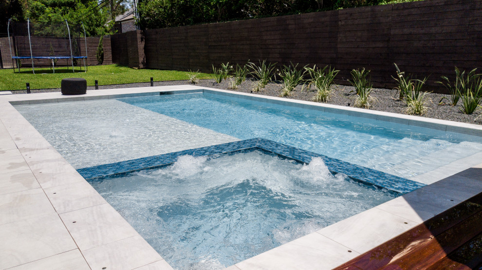 Ispirazione per una grande piscina contemporanea rettangolare dietro casa con pavimentazioni in pietra naturale