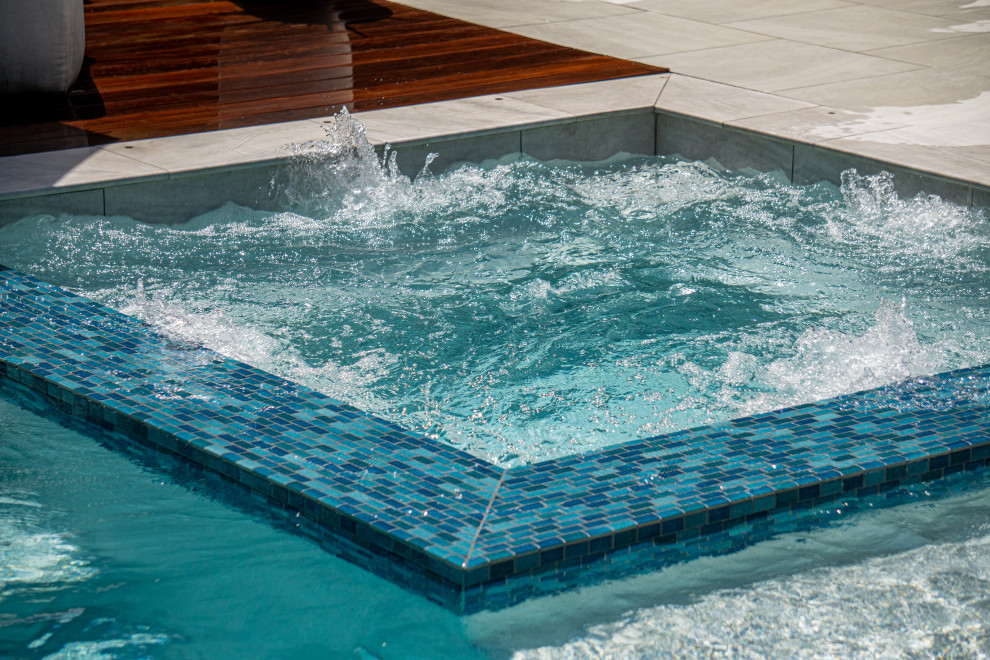 This is an example of a large contemporary back rectangular swimming pool in Houston with natural stone paving.