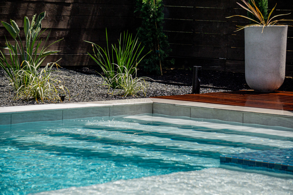 Immagine di una grande piscina design rettangolare dietro casa con pavimentazioni in pietra naturale