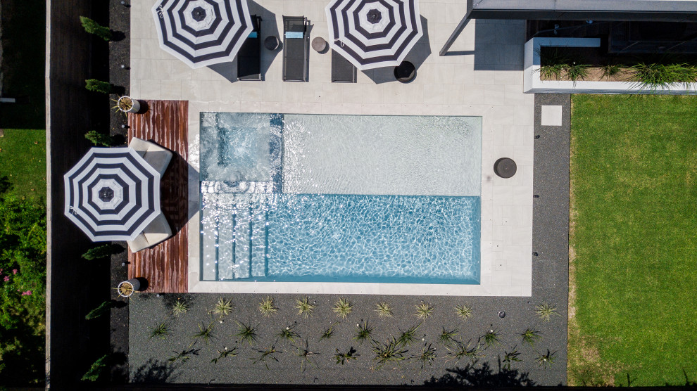 Example of a large trendy backyard stone and rectangular pool design in Houston